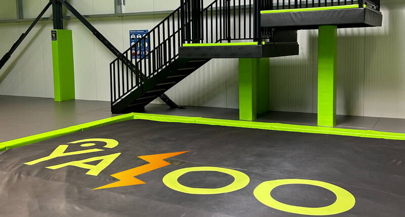Aire de réception rembourrée avec logo Yazoo, conçue pour des activités de trampoline et des sauts en toute sécurité.