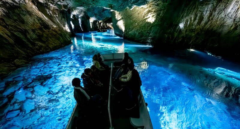Ein Boot gleitet über das blau leuchtende Wasser des Lac Souterrain St‑Léonard und zeigt die eindrucksvolle Höhlenwelt im Wallis.