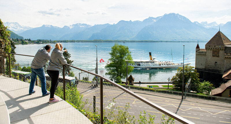 Panorama über den Genfersee, die Berge der Riviera Waadt und ein Belle‑Époque‑Schiff, das am Schloss Chillon vorbeifährt.