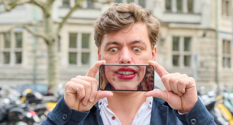 Besucher hält Illusionskarte vor das Gesicht – im Hintergrund die Zürcher Altstadt.