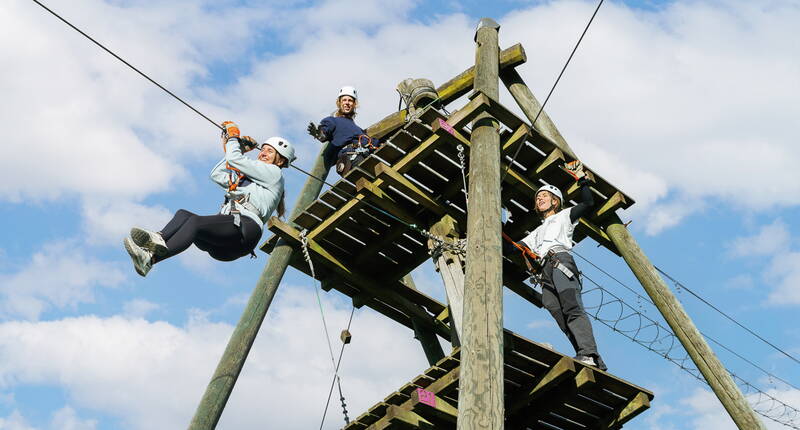 Partecipanti si lanciano dalla torre del parco verso la zipline – un momento emozionante per grandi e piccoli.