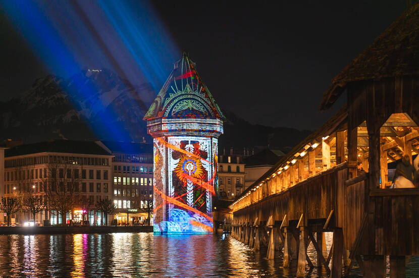 Lichtkunst auf der Kapellbrücke – Wahrzeichen neu inszeniert Der Wasserturm und die Kapellbrücke, ikonische Wahrzeichen Luzerns, werden durch kunstvolle Lichtprojektionen in ein spektakuläres Farbenspiel verwandelt.