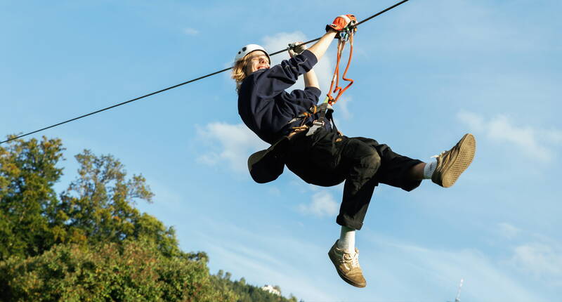 Una persona scivola sulla zipline del parco avventura Rigi – un’esperienza perfetta per chi ama l’azione.