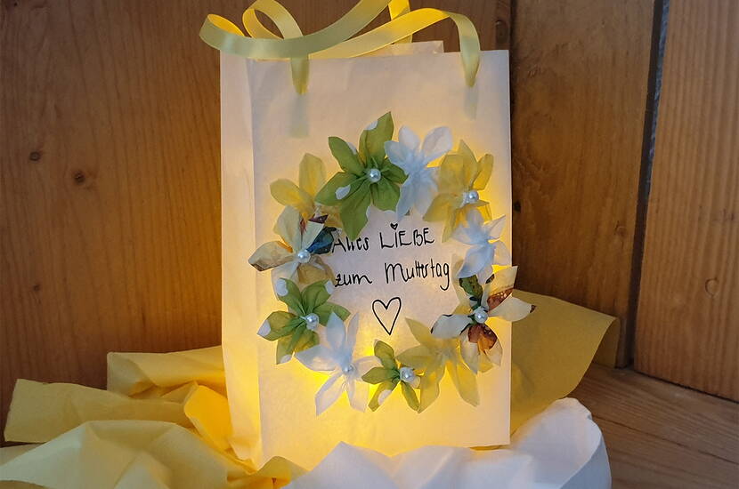 Anleitung Muttertagsgeschenk basteln. Für wenig Geld entsteht im Handumdrehen ein wunderschöne Geschenktüte zum Muttertag. Alles, was du dazu benötigst, ist eine Butterbrottüte, verschiedene Servietten, Dekomaterial und unsere Vorlagen mit Sprüchen zum Dank, welche du kostenlos herunterladen kannst.