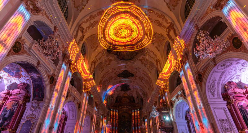 À l'intérieur de l'église, des installations lumineuses fascinantes resplendissent dans des tons jaunes et rouges chaleureux et créent une atmosphère mystique lors du Festival des Lumières de Lucerne.