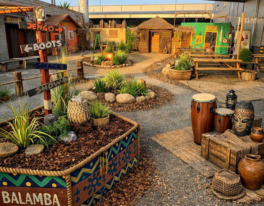 Das farbenfrohe Balamba Village begeistert mit Holzhütten, Pflanzeninseln und liebevollen Details. Wegweiser, Trommeln und rustikale Dekorationen schaffen eine einladende Atmosphäre für Spiel, Shows und Snacks.