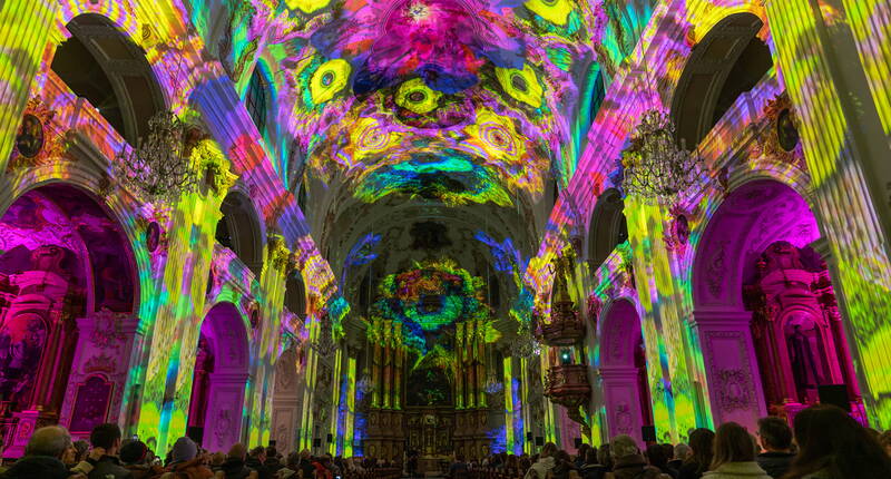 Die Kirche erstrahlt in intensiven Farben und Mustern. Die Lichtinstallation fasziniert mit dynamischen Projektionen und zieht Besucherinnen und Besucher in ihren Bann.