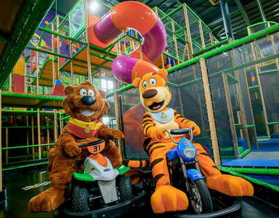 Deux mascottes amusantes parcourent un univers de jeux coloré et offrent rires et plaisir aux enfants.