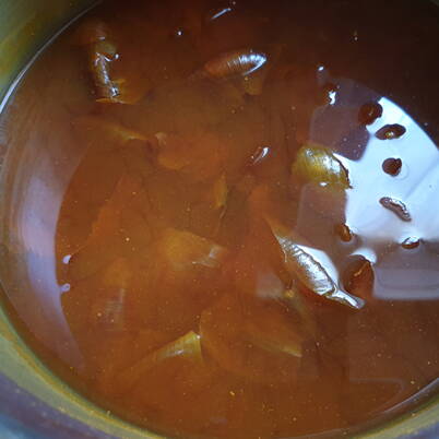 Une casserole contenant un bain chaud et brun de pelures d’oignons, dans lequel les pigments végétaux passent doucement dans l’eau.